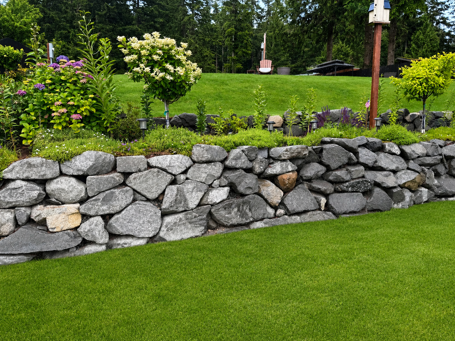 Finished natural stone retaining wall along a manicured lawn